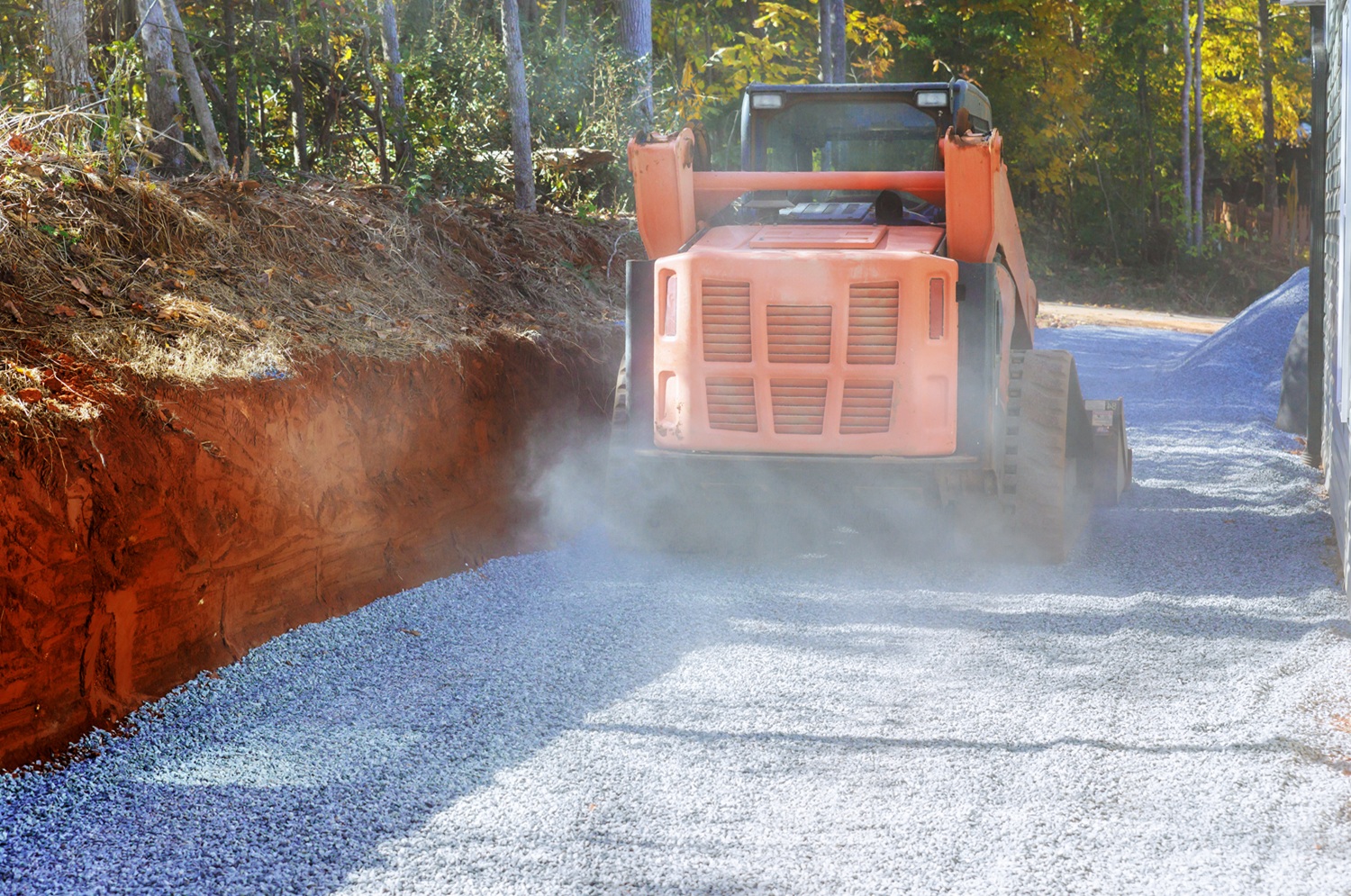 Using tractor to lay crushed stone gravel fill on top surface of new road as a basis graved crushed stone gravel installs